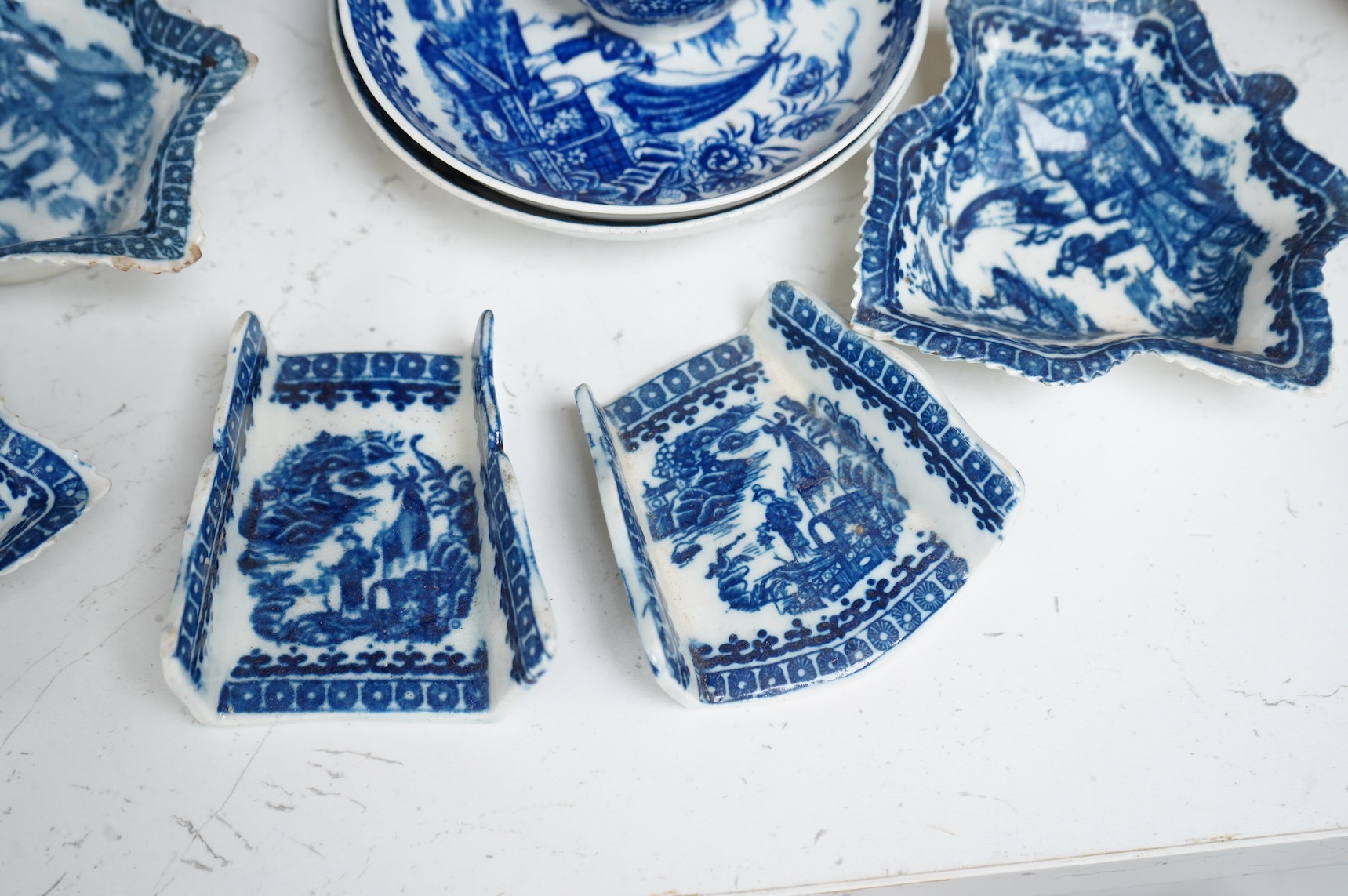 A group of 18th century Worcester or Caughley blue and white ‘Fisherman and Cormorant’ pattern wares; two asparagus dishes, three leaf pickle dishes, a cup and two saucers and a large dish- 18cm diameter (9).